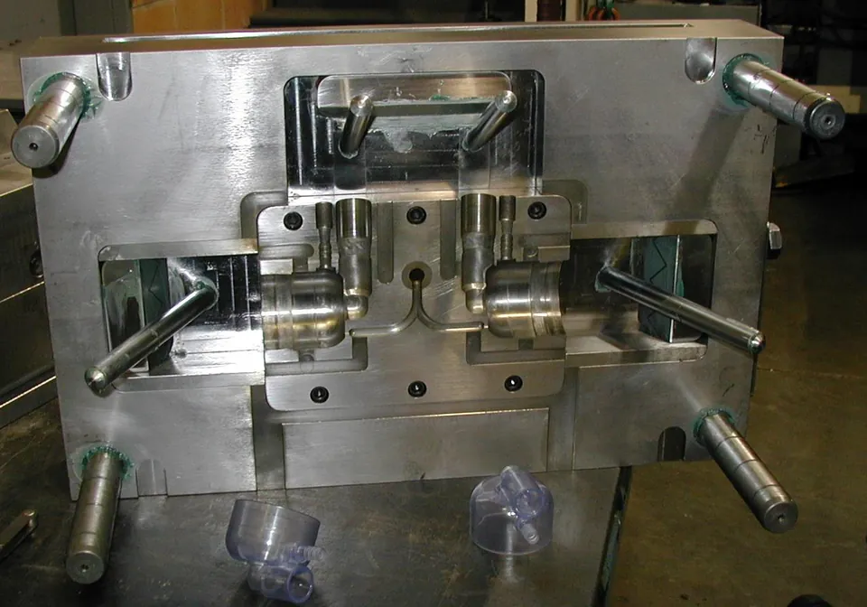 Open injection mold with clear molded cups resting in front of it